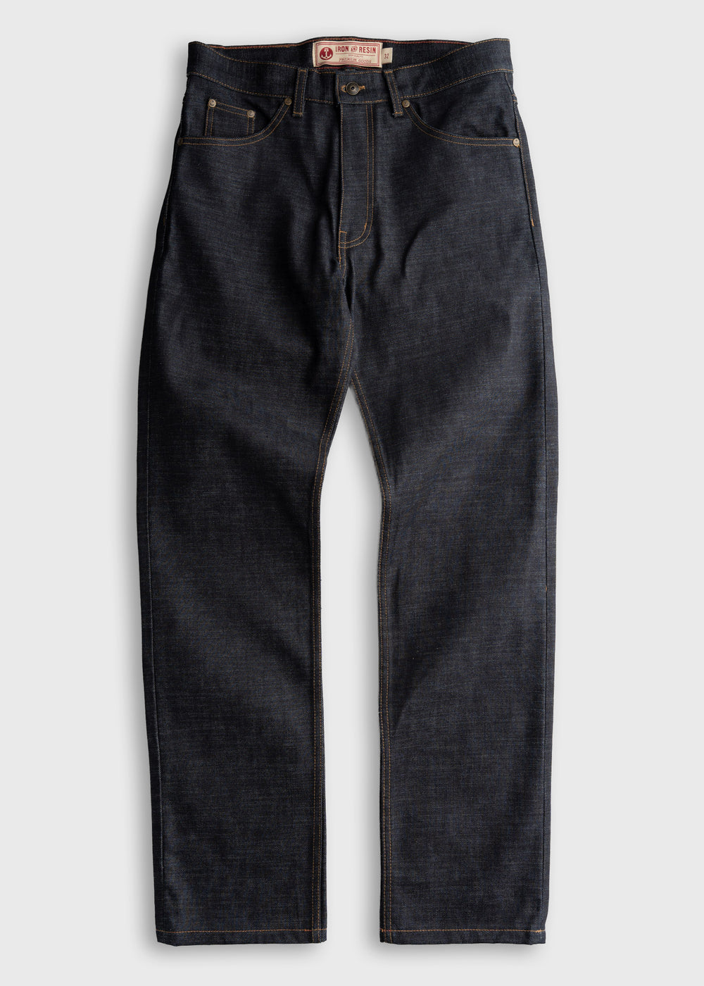 Dark denim jeans with contrast stitching, featuring a button fly and five-pocket design, laid flat on a light background.