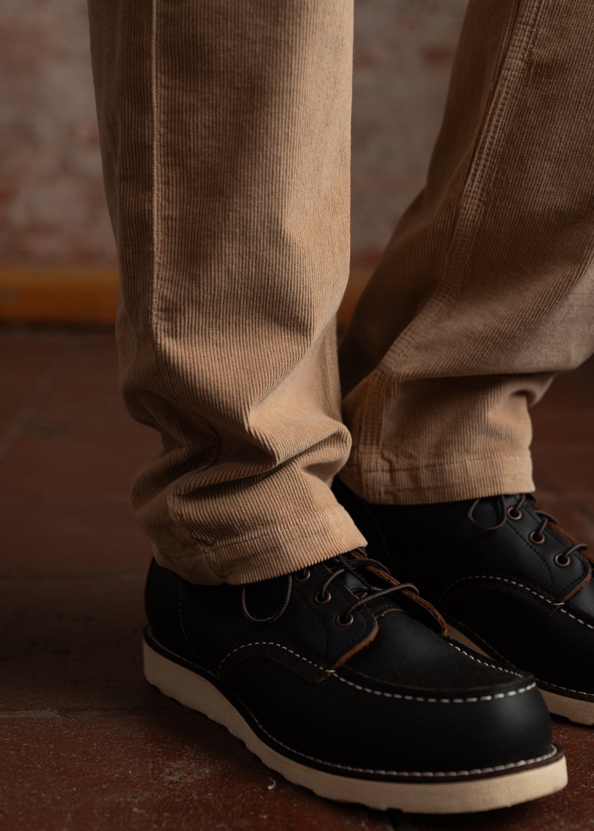 Beige corduroy pants paired with black leather shoes on a tiled floor, creating a casual yet stylish look.