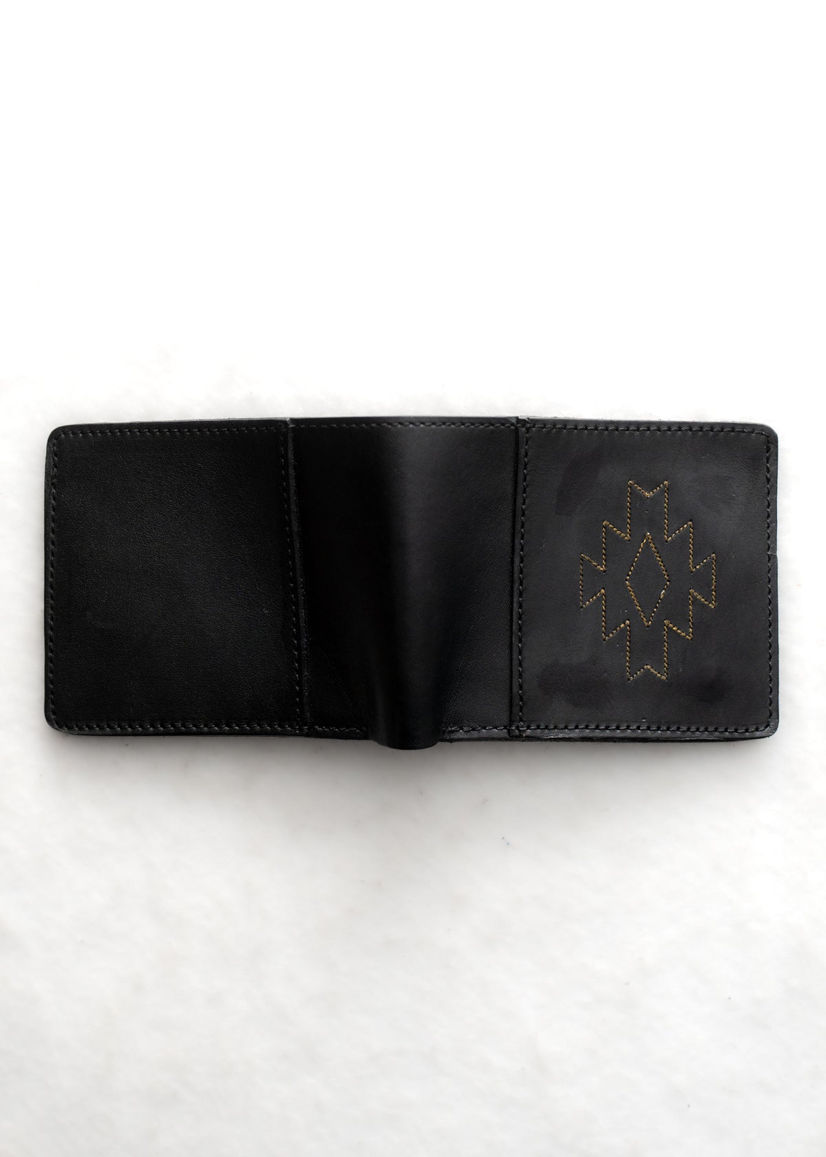 Open black leather wallet with geometric stitching on the right side, placed on a white background.