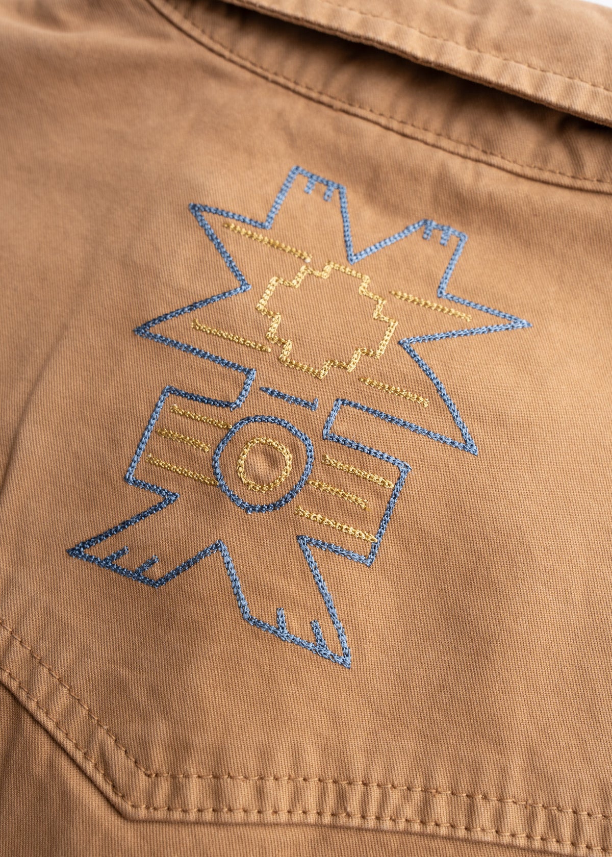 Brown fabric with blue and yellow geometric embroidery, featuring star and circle patterns, creates a striking visual contrast.