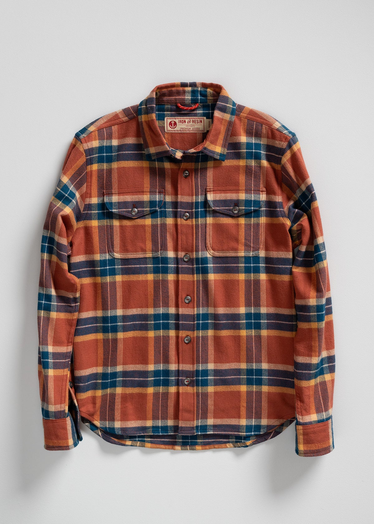 Orange and blue plaid flannel shirt with buttoned pockets, laid flat on a white background. Iron and Resin label visible.