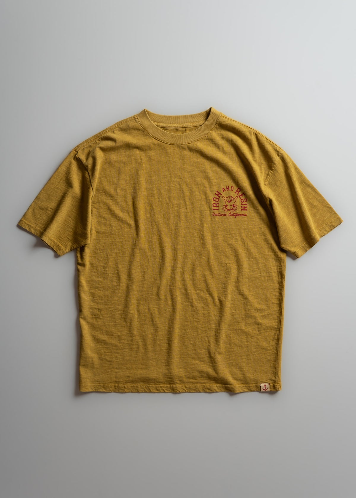 Yellow T-shirt with "Iron and Resin" logo in red, featuring an anchor design, laid flat on a light gray background.