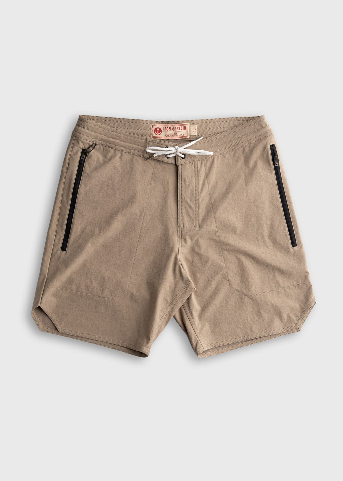 Tan shorts with black zippered pockets and a white drawstring, labeled "Iron & Resin," on a plain white background.