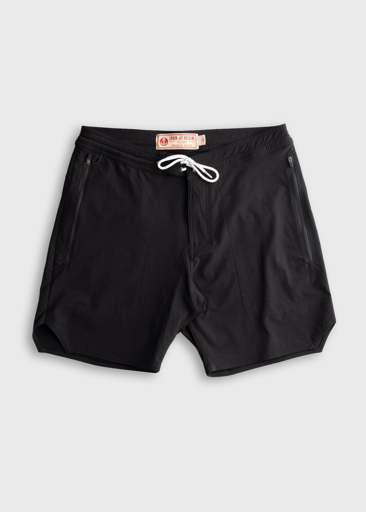 Black swim trunks with white drawstring and zippered pockets, featuring an Iron & Resin label on a light gray background.