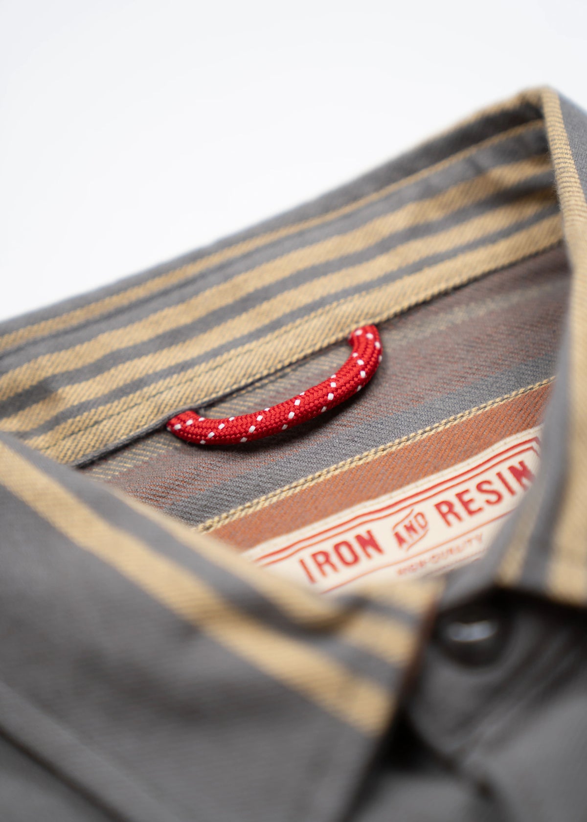 Close-up of a gray shirt collar with beige stripes, featuring a red loop and an Iron and Resin label inside.