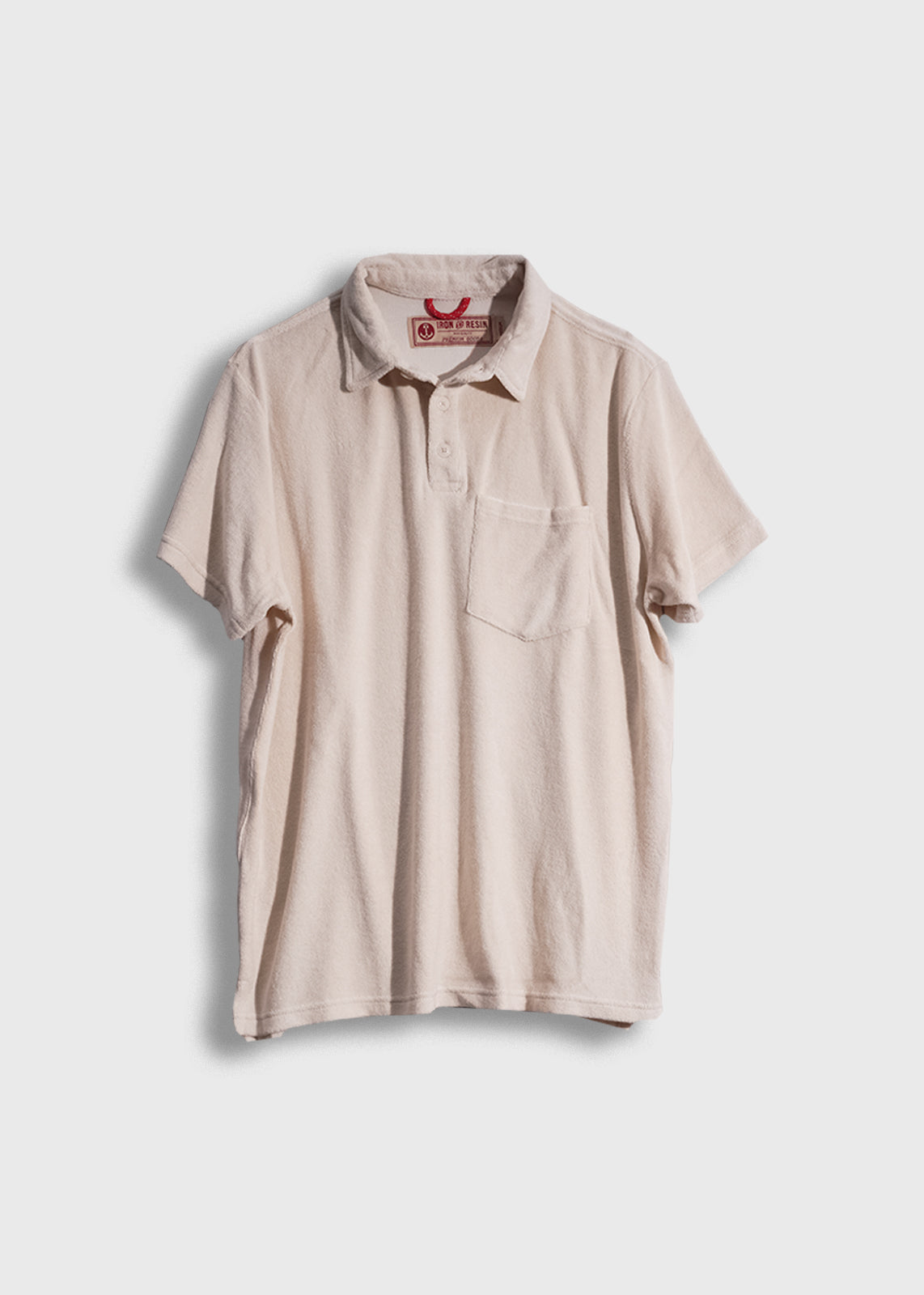 Beige short-sleeve polo shirt with a chest pocket, displayed on a white background, featuring a red label inside the collar.