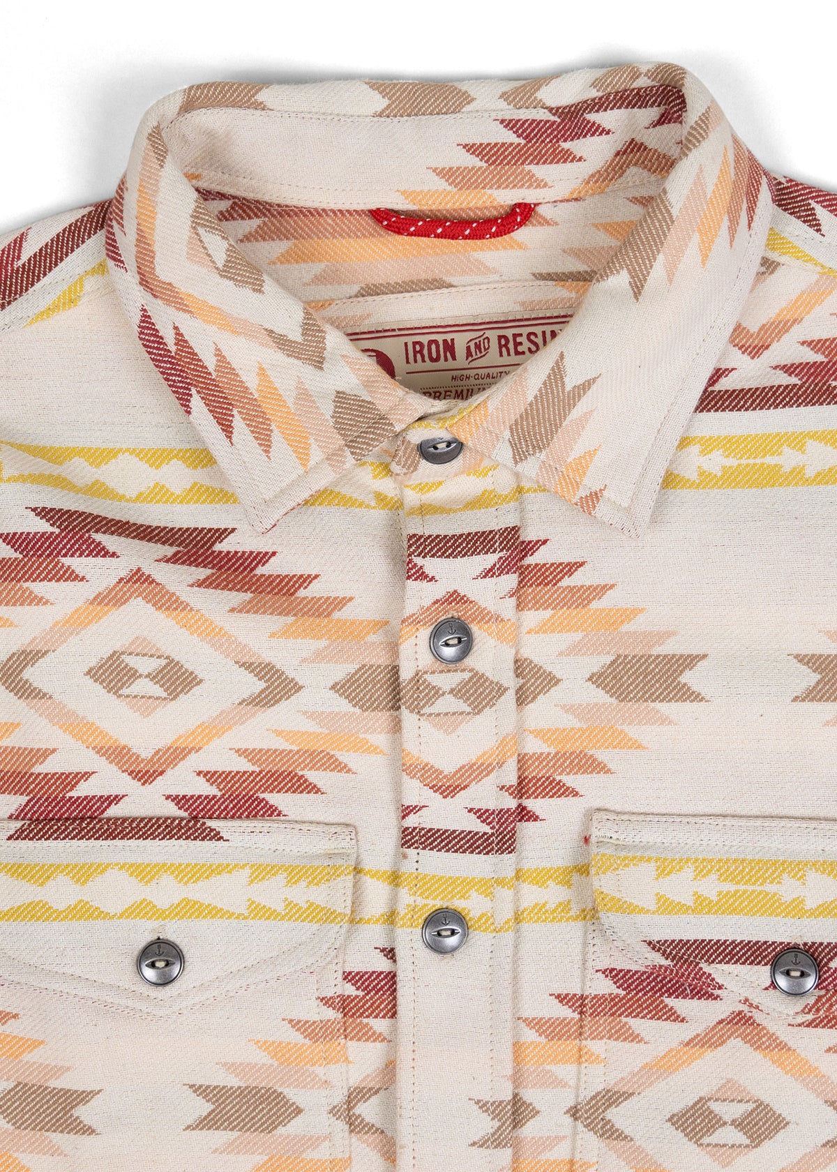 Patterned shirt with geometric designs in earthy tones, featuring buttons and pockets. Label reads "Iron and Resin Premium."