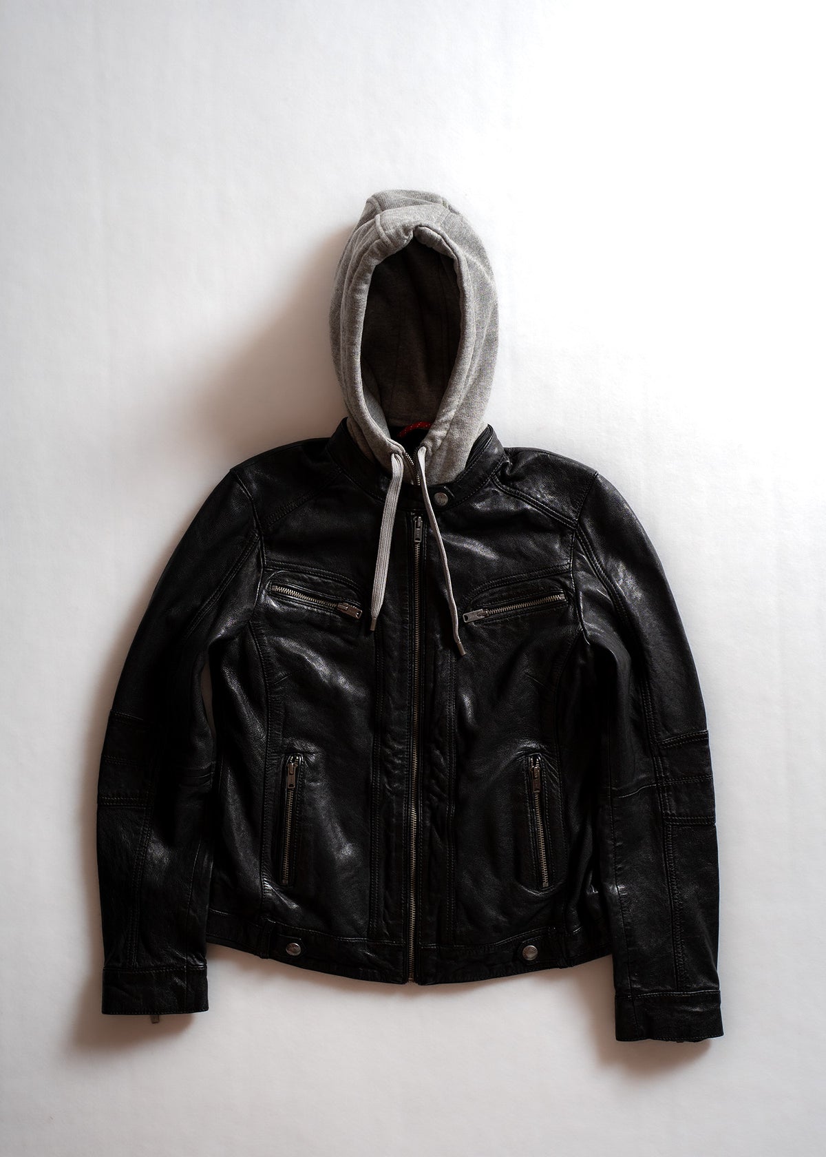 Black leather jacket with a gray hood on a white background, featuring multiple zippers and a casual, stylish design.