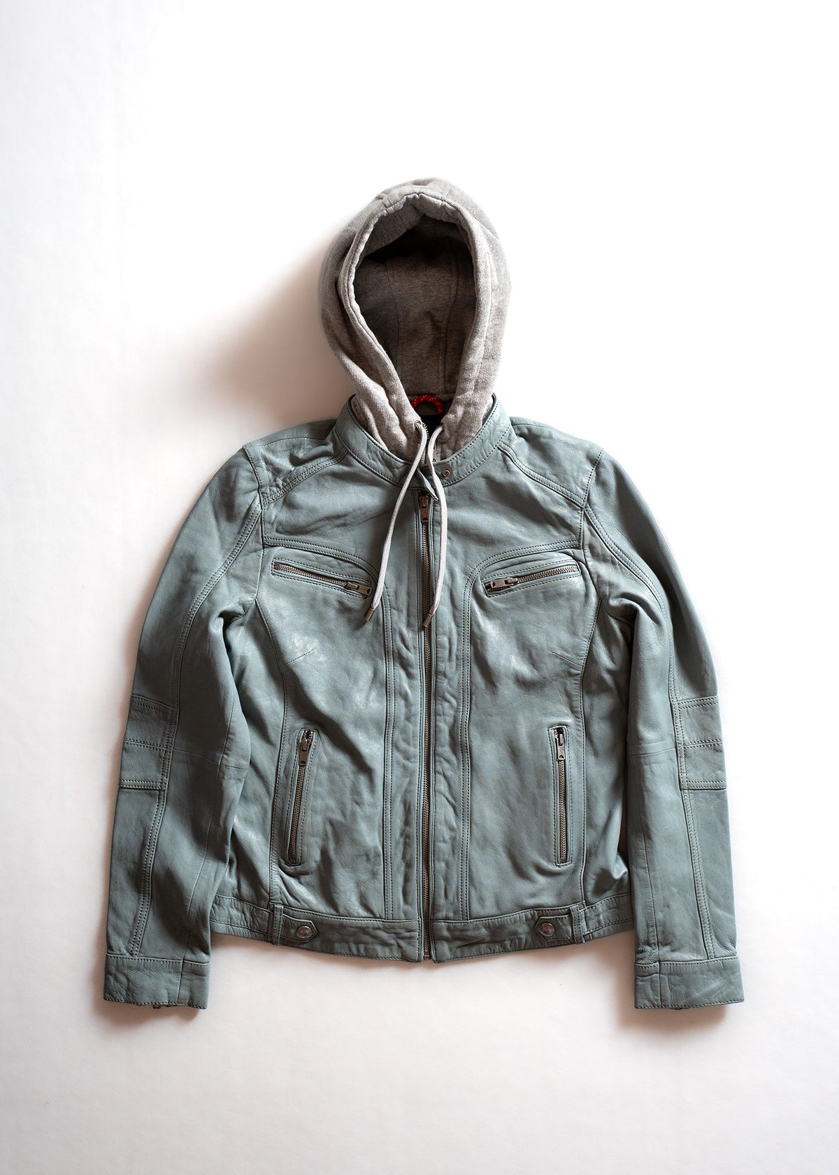 A gray leather jacket with a hood, featuring multiple zippers, is laid flat on a white background, highlighting its design.