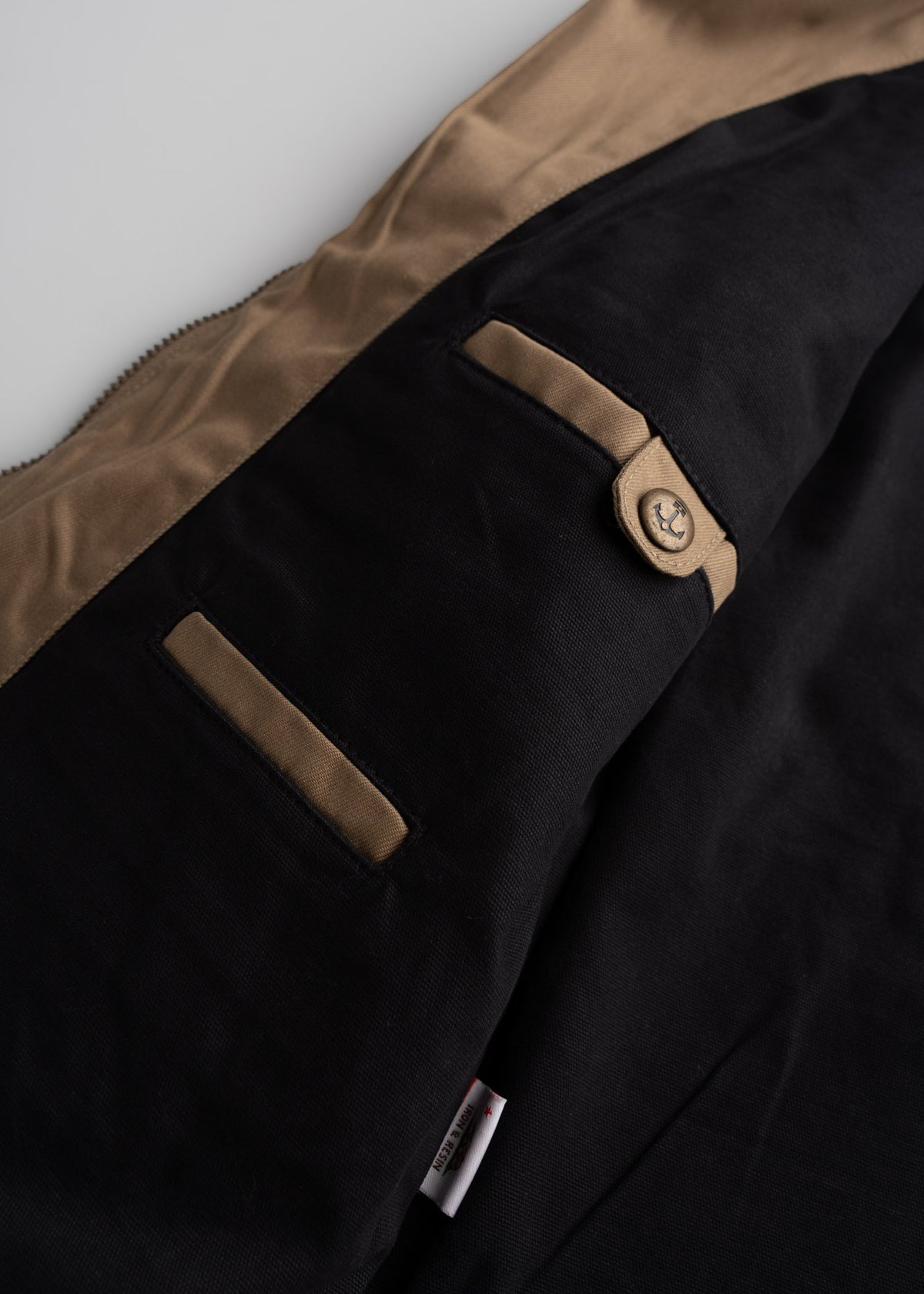 Close up of inner pockets on jacket, showcasing top entry design, custom buttons and utility storage