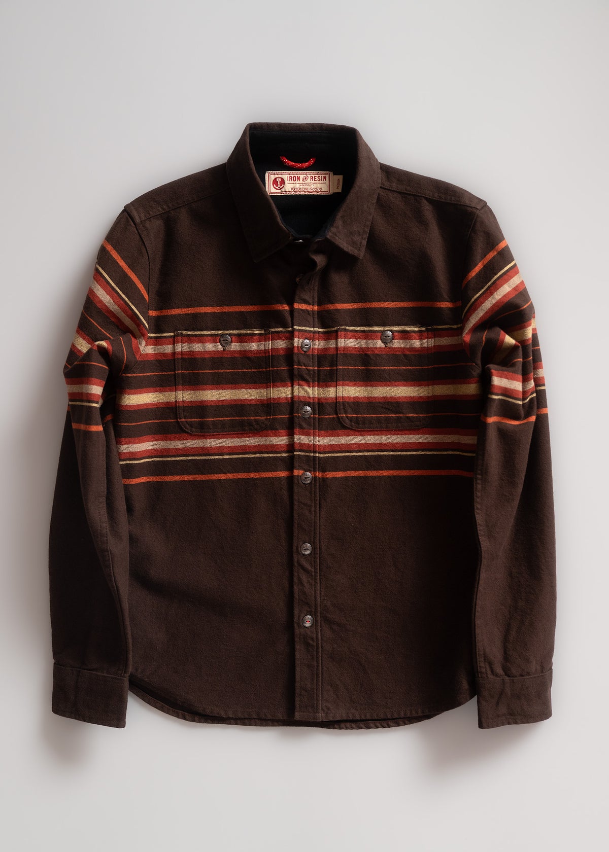 Brown button-up shirt with orange and red horizontal stripes, featuring two chest pockets, laid flat on a light background.