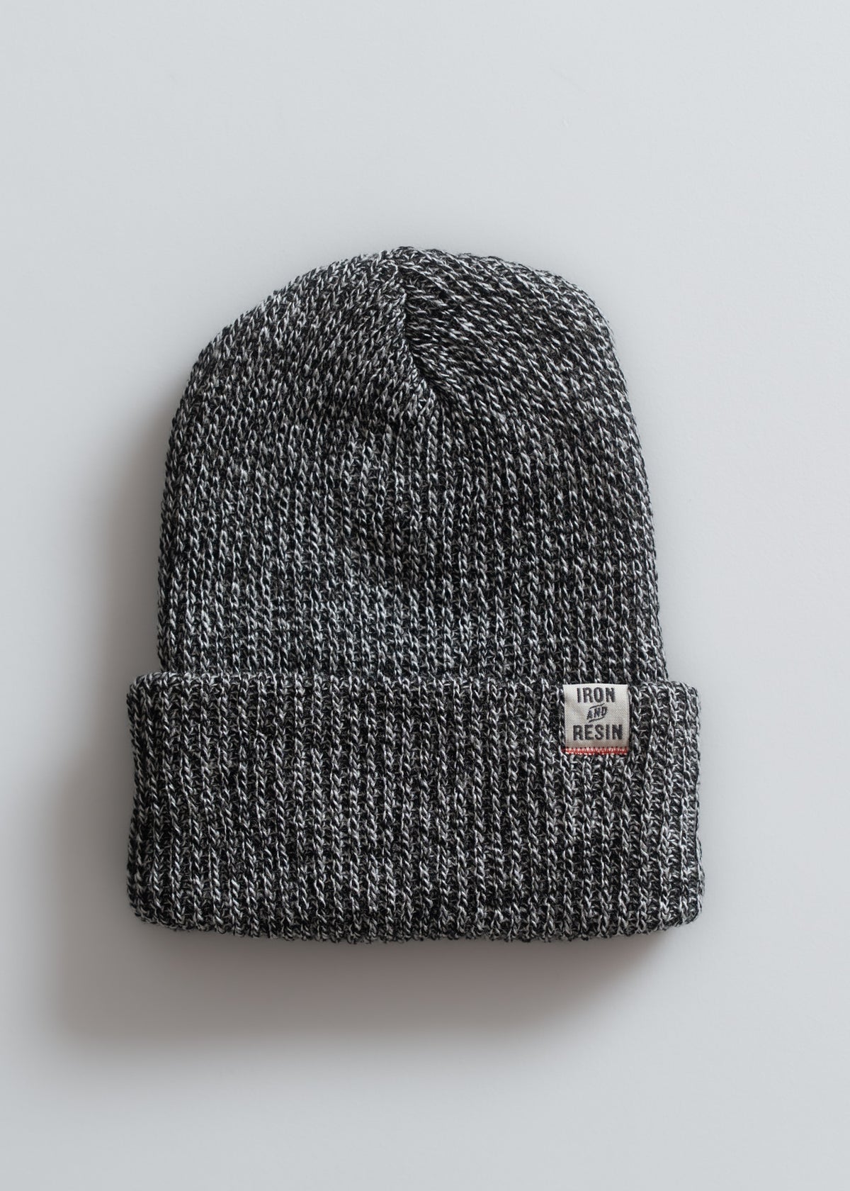 Gray knit beanie with a folded brim and "Iron and Resin" label, displayed on a light background, showcasing texture and style.