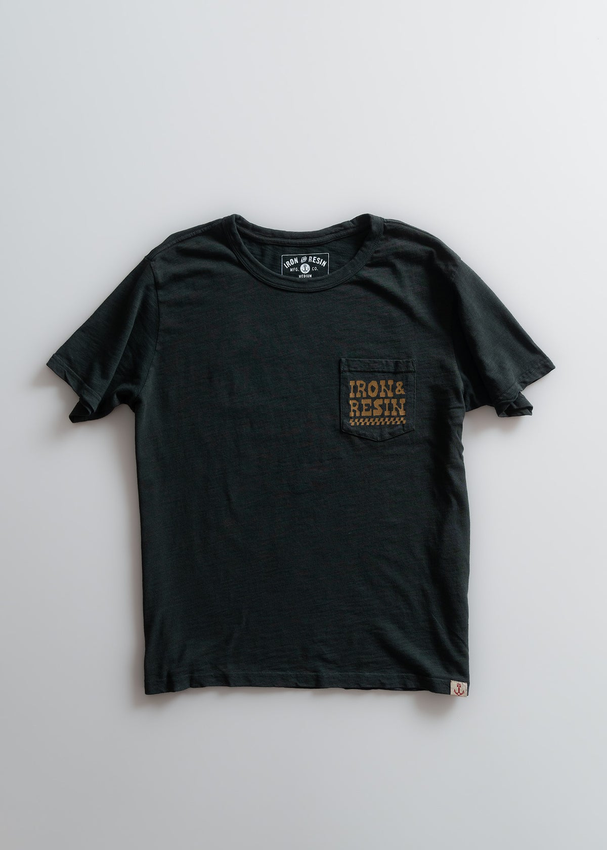 Black T-shirt with "Iron & Resin" text on chest pocket, laid flat on a light background. Simple and stylish design.