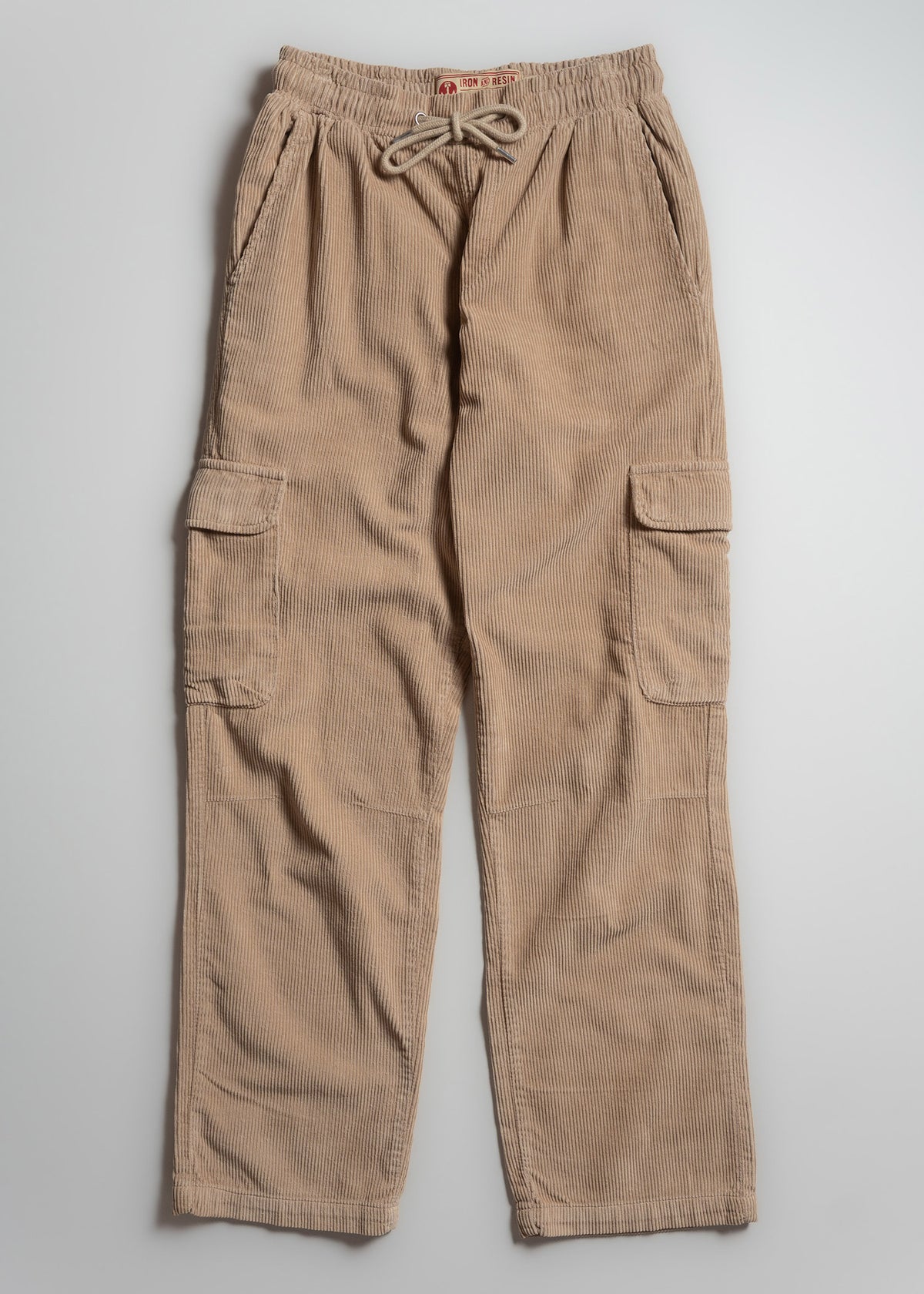 Beige corduroy cargo pants with drawstring waist and side pockets, laid flat on a light gray background.