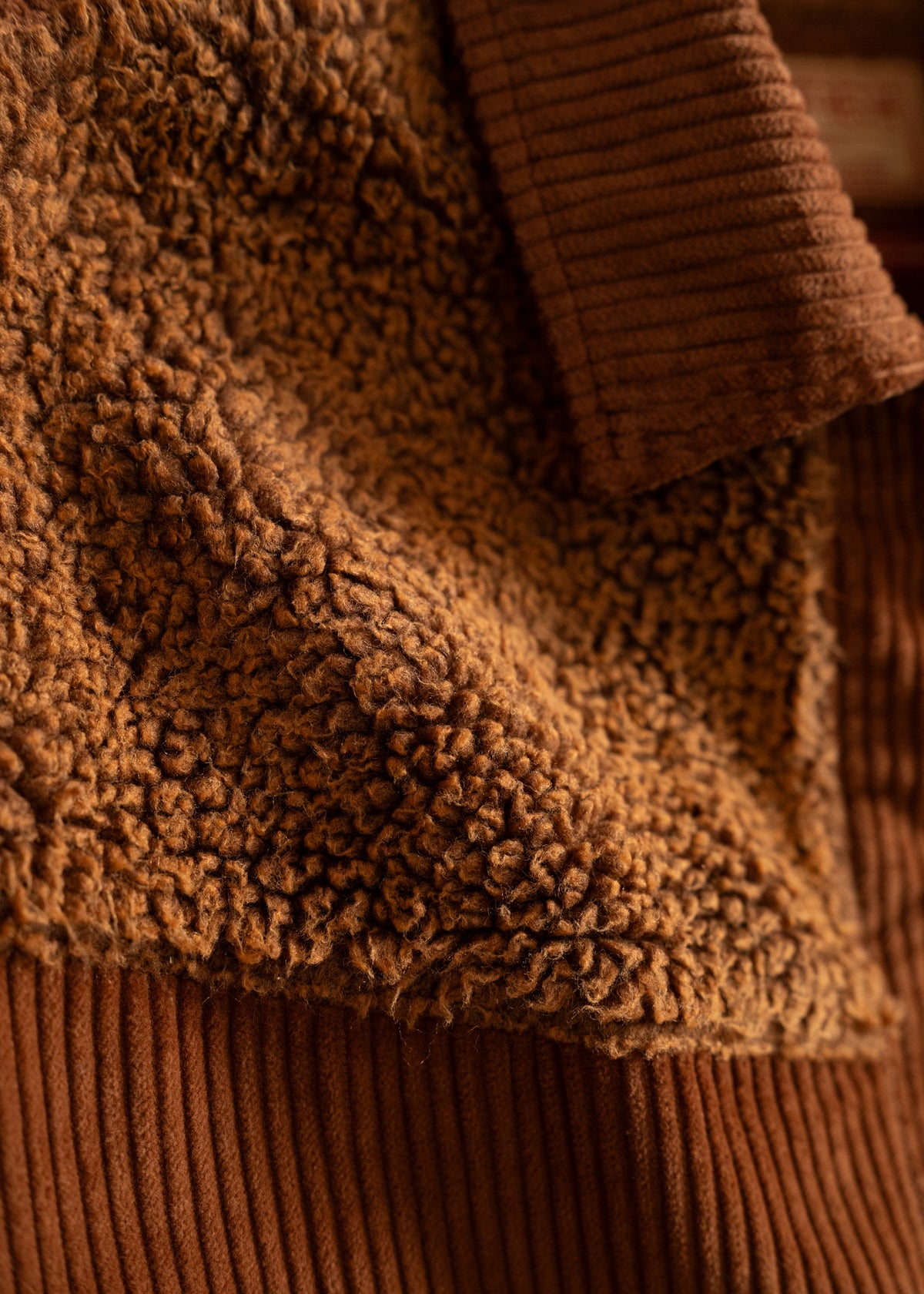 Close-up of a brown textured fleece jacket with ribbed collar, showcasing its soft, cozy fabric and detailed stitching.