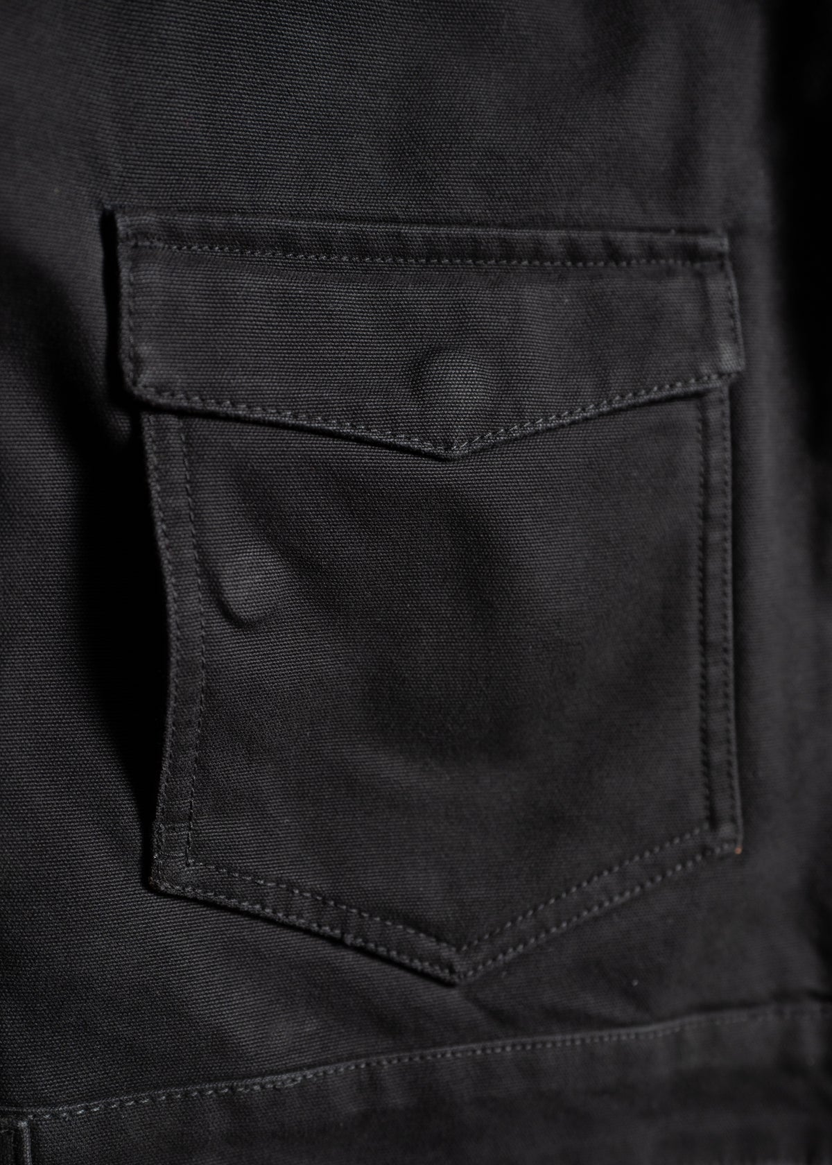 Close-up of a black fabric pocket with a flap, showing detailed stitching and texture, highlighting the material's quality.