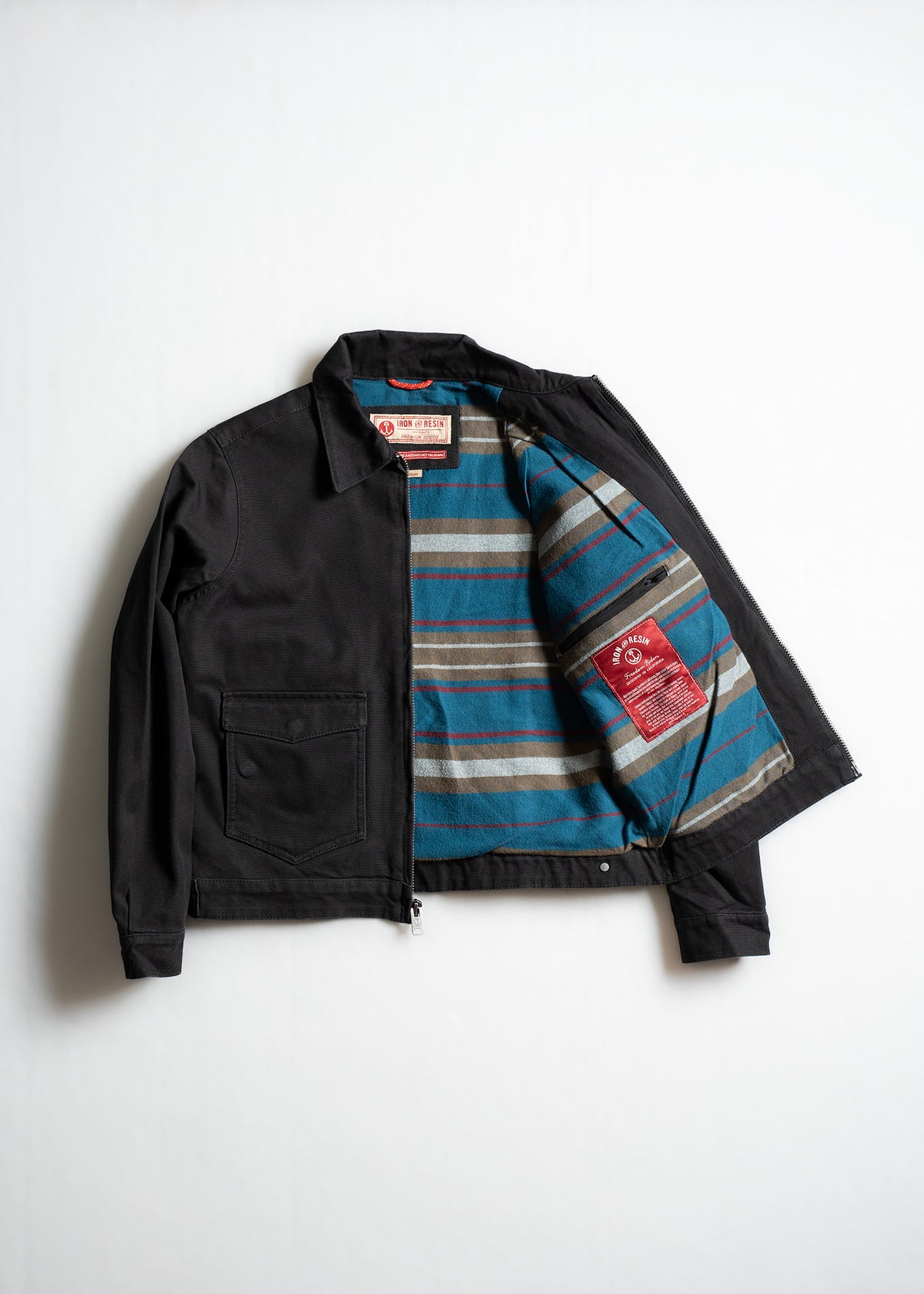 Black jacket with open front reveals striped blue, brown lining. Features a chest pocket and visible red label inside.