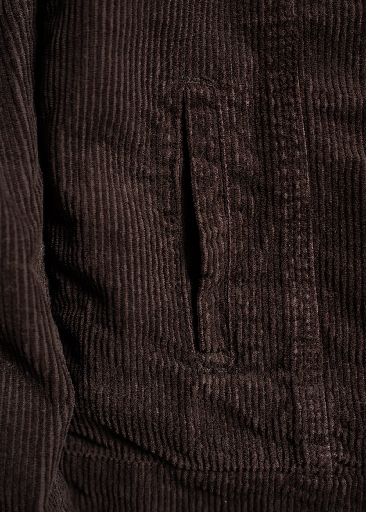 Close-up of a brown corduroy jacket pocket, highlighting the textured fabric and vertical ridges.
