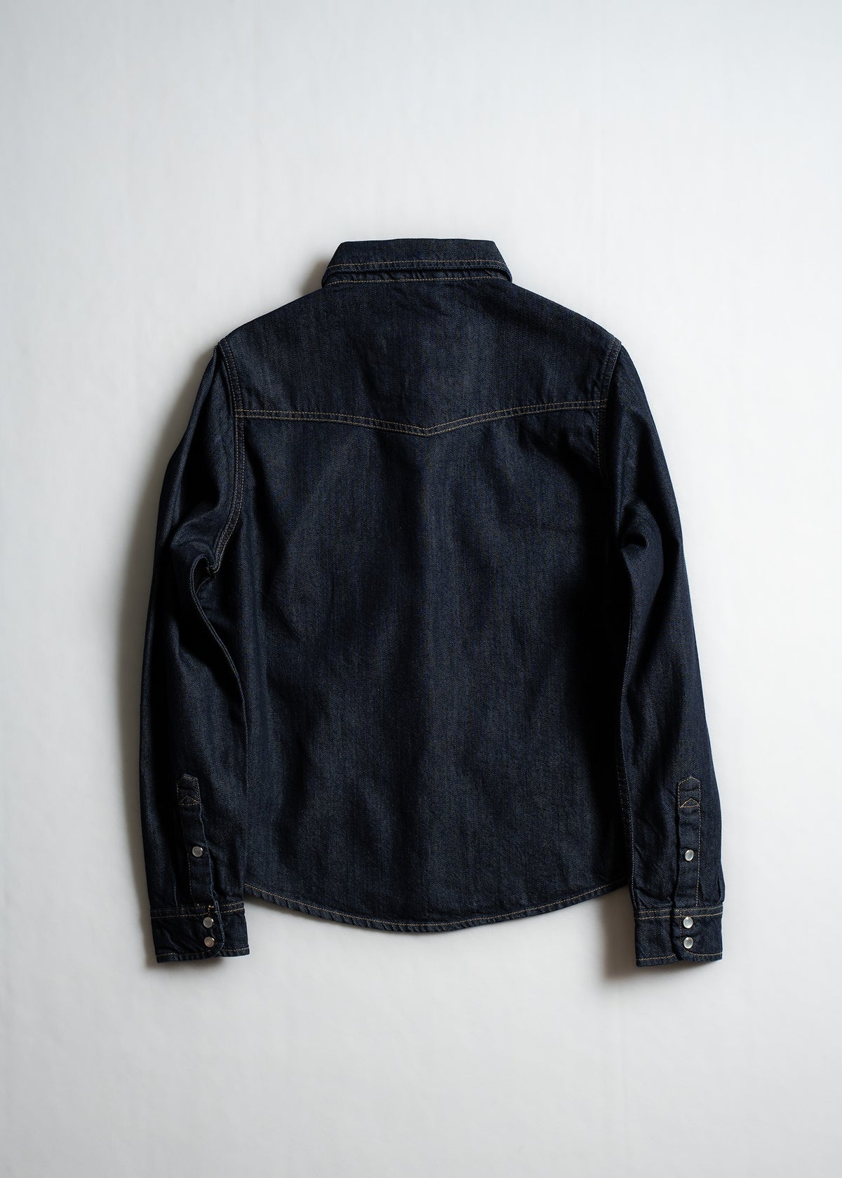 Dark denim shirt displayed on a white background, showing back details and long sleeves with buttoned cuffs.